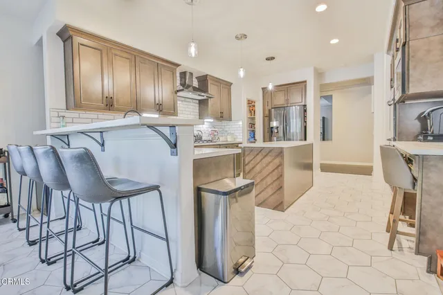 a kitchen with stainless steel appliances granite countertop a table chairs and a refrigerator