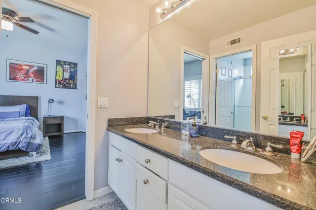 a bathroom with a granite countertop double vanity sink and a mirror