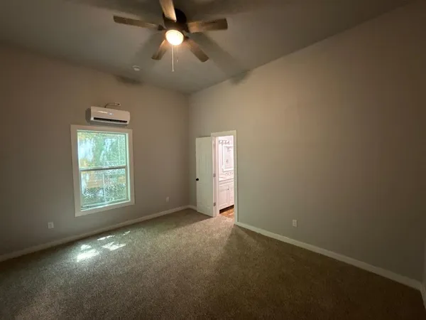 a view of an empty room with a window and a kitchen