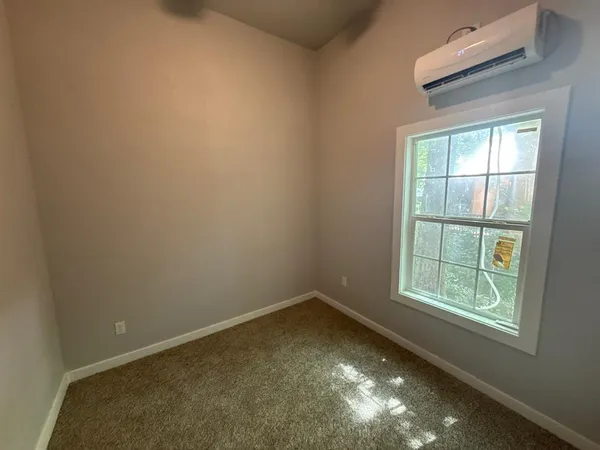 an empty room with windows and fan