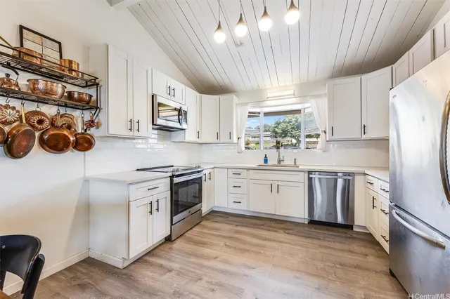 a kitchen with stainless steel appliances granite countertop a sink a stove a refrigerator cabinets and a window