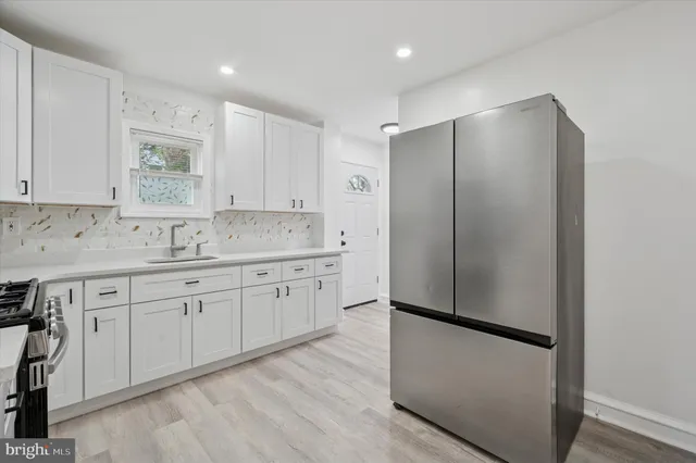 a kitchen with stainless steel appliances granite countertop a refrigerator a sink and white cabinets