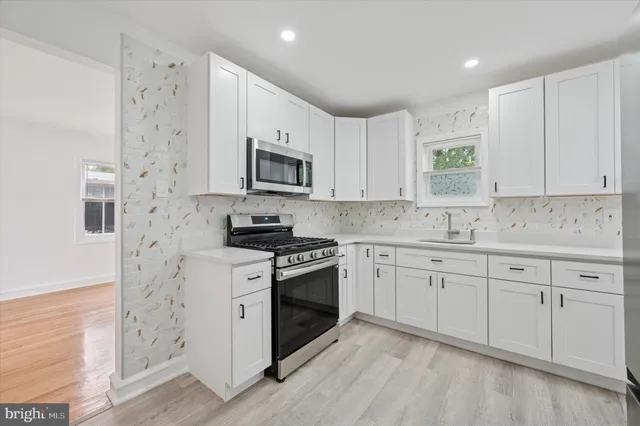 a kitchen with granite countertop white cabinets sink and stainless steel appliances