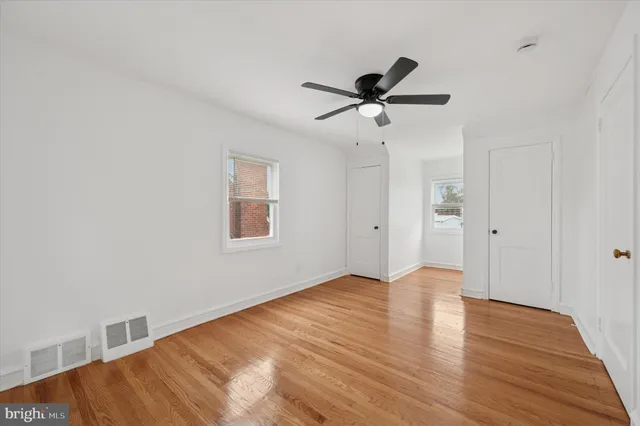 a view of empty room with wooden floor and fan