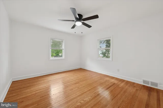 an empty room with wooden floor and ceiling fan