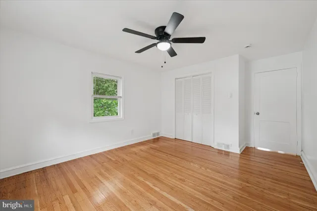 a view of empty room with wooden floor and ceiling fan