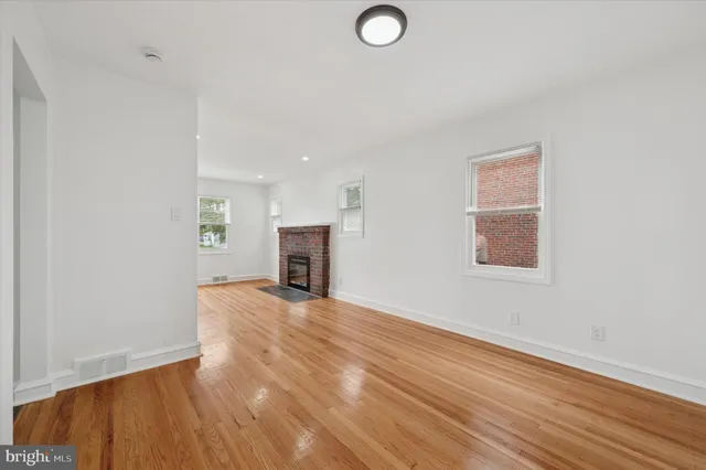 a view of empty room with wooden floor and fireplace