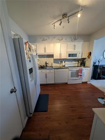 a kitchen with granite countertop a stove a sink a counter space and cabinets