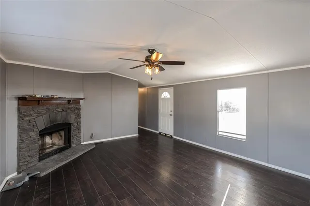 a view of an empty room with wooden floor fireplace and a window