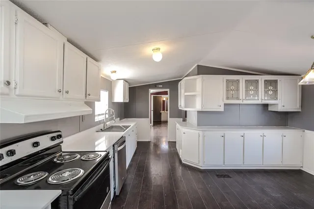 a kitchen with stainless steel appliances a stove a sink dishwasher and a refrigerator with wooden floor