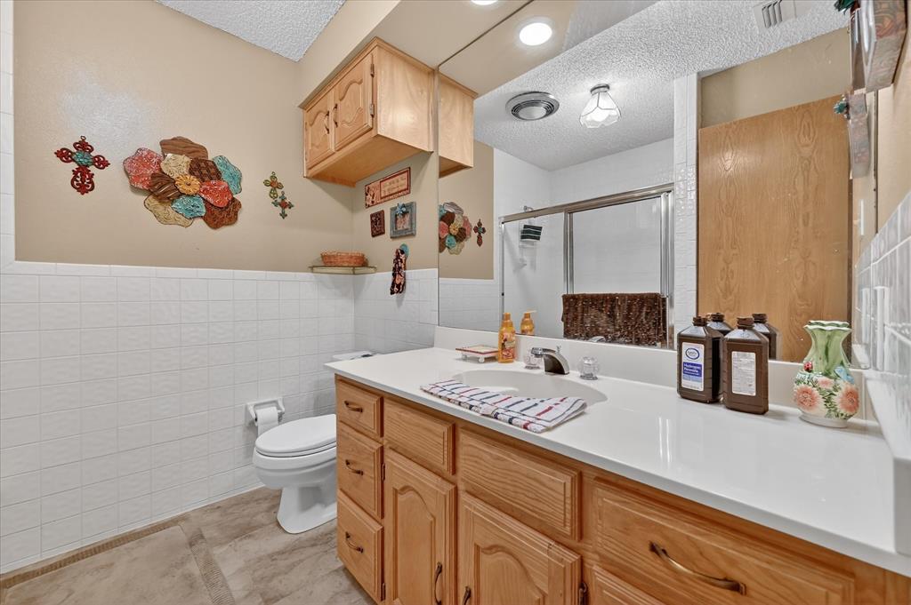 1605 Heather Court Cleburne, TX 76033 - Photo 19 of 33 a bathroom with a granite countertop sink a toilet and a mirror