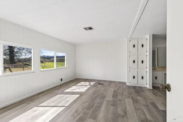 a view of an empty room with window and wooden floor