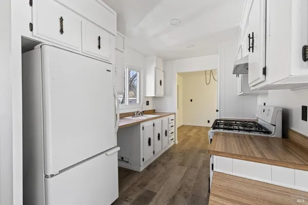 a kitchen with stainless steel appliances a refrigerator a sink and white cabinets