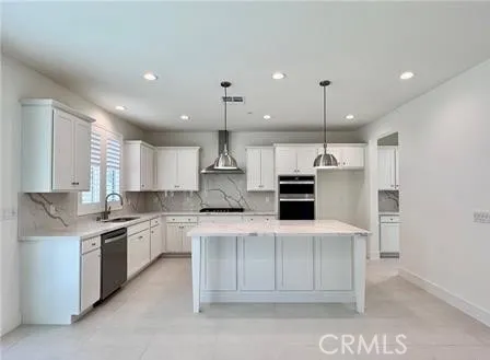 a kitchen with stainless steel appliances kitchen island granite countertop a sink and white cabinets