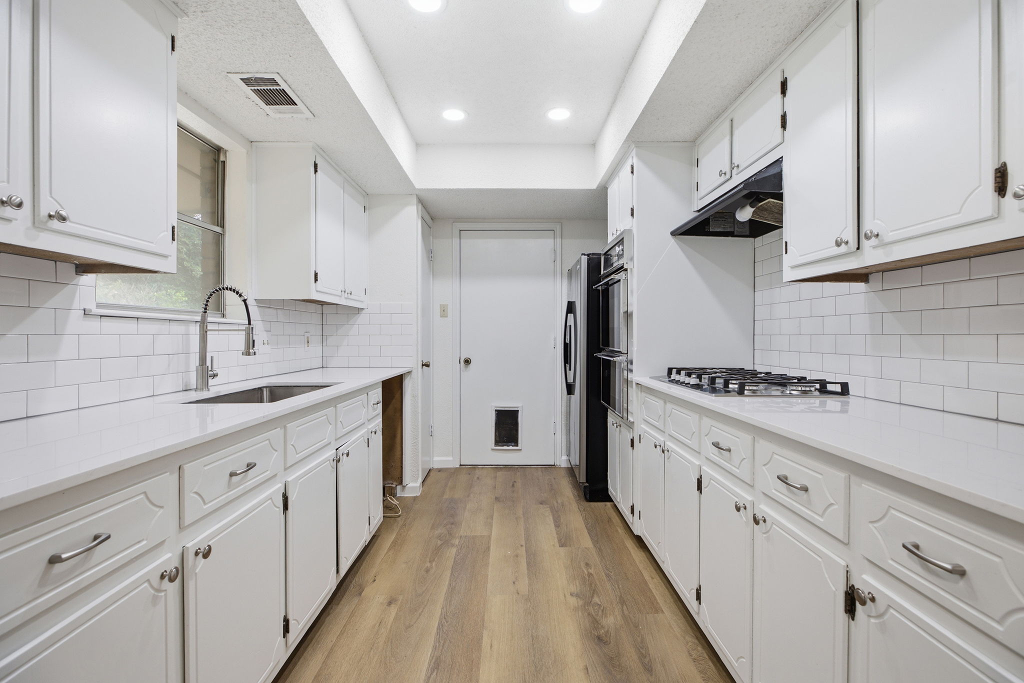 7205 Beckett Road Austin, TX 78749 - Photo 11 of 40 A well-lit kitchen presents bright white cabinetry, pristine subway tile backsplash, and modern appliances.