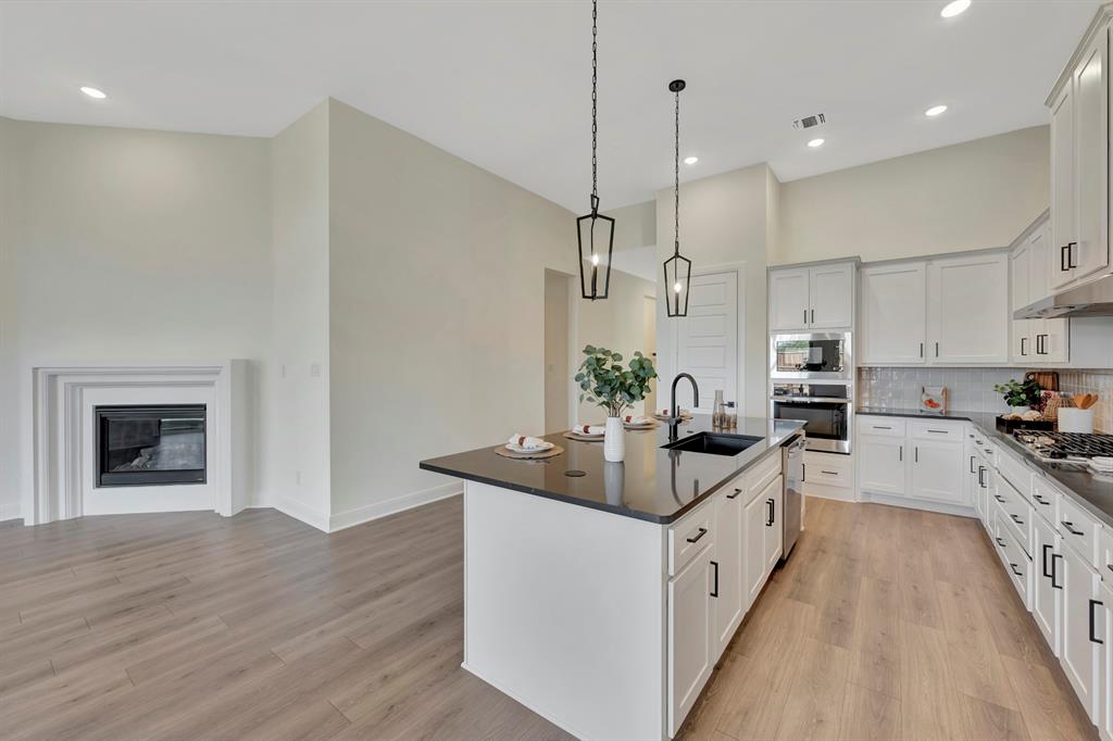 2901 Long Trail Mansfield, TX 76063 - Photo 18 of 28 a white kitchen with stainless steel appliances granite countertop a sink a stove and a wooden floors