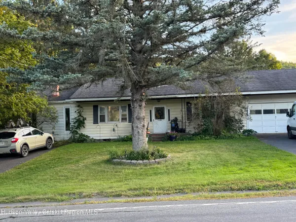 a front view of a house with a garden and trees