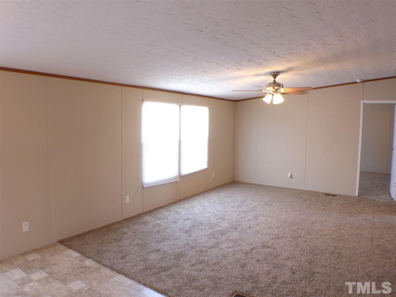 7515 Bill Love Road Willow Spring, NC 27592 - Photo 7 of 20 an empty room with a chandelier fan and windows
