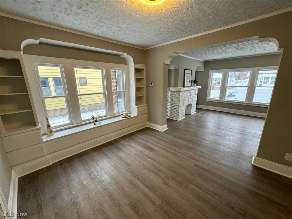 3333 Berea Road Cleveland, OH 44111 - Photo 4 of 34 Unfurnished living room featuring dark wood-type flooring, a brick fireplace, and a healthy amount of sunlight