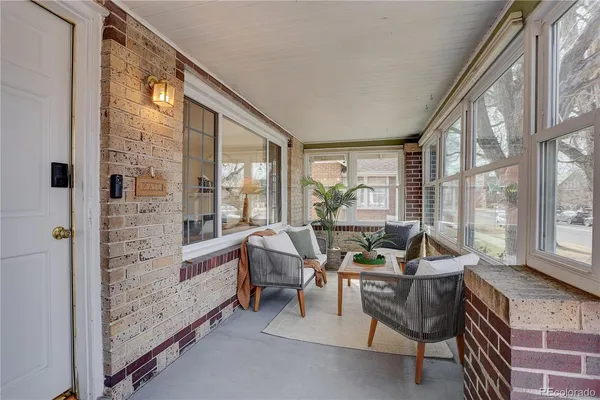 a living room with furniture large windows and wooden floor