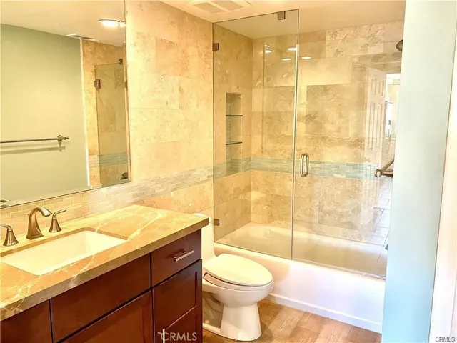 a bathroom with a granite countertop sink a toilet and shower