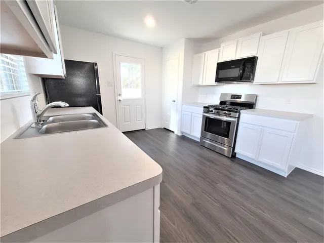 a kitchen with granite countertop a stove and a wooden floor