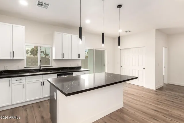 a kitchen with stainless steel appliances granite countertop a sink a stove and a wooden floor