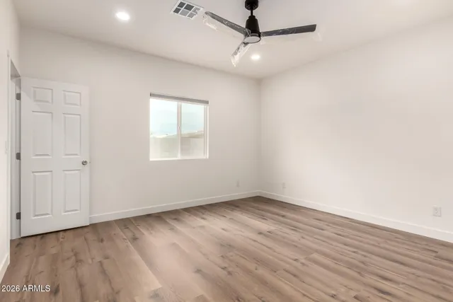 an empty room with wooden floor fan and windows