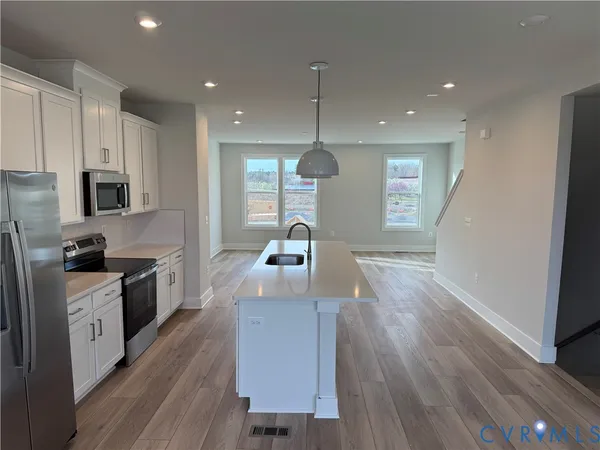 a open kitchen with kitchen island wooden floors appliances and cabinets