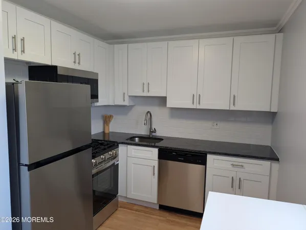 a kitchen with white cabinets and refrigerator