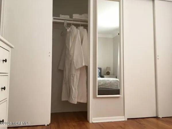 a walk in closet with wooden floor