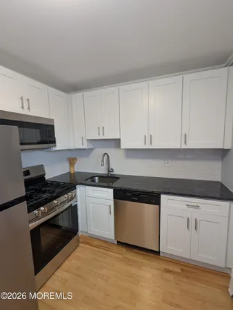 a kitchen with granite countertop white cabinets and stainless steel appliances