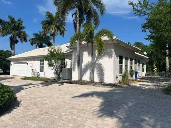 a view of a house with a yard and palm trees