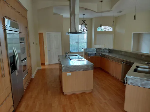 a kitchen with granite countertop a refrigerator a stove and wooden floor