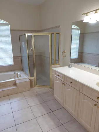 a spacious bathroom with a granite countertop sink a mirror and a bathtub