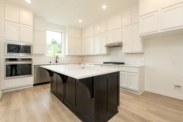 a kitchen with a sink cabinets stainless steel appliances and a window
