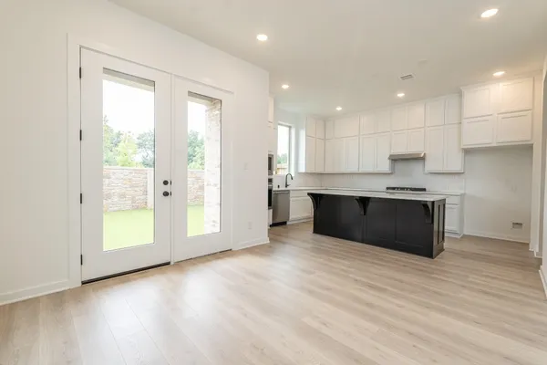 a large kitchen with stainless steel appliances granite countertop a large counter top a wooden floors and a large window