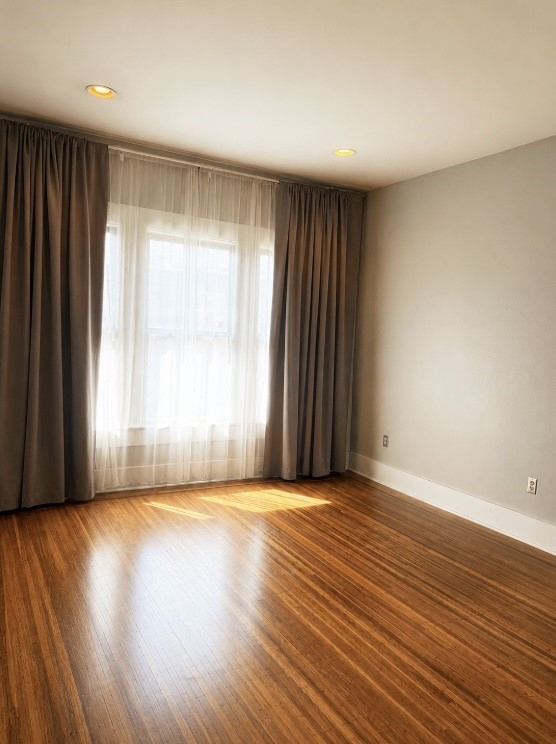4530 Walker Street Houston, TX 77023 - Photo 12 of 17 an empty room with wooden floor and windows with curtains