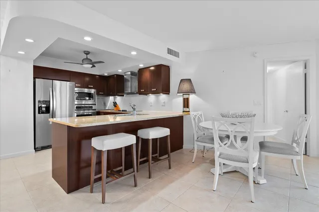 a kitchen with stainless steel appliances kitchen island granite countertop a table and chairs in it