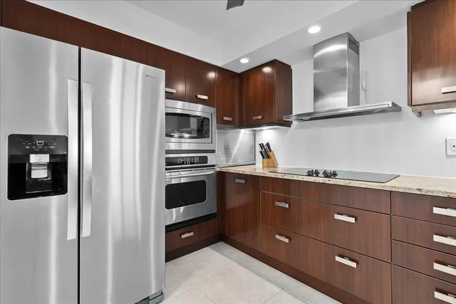 a kitchen with stainless steel appliances granite countertop a refrigerator a stove a sink and a microwave