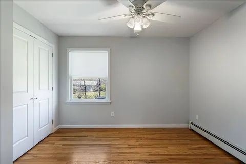 an empty room with wooden floor chandelier fan and windows