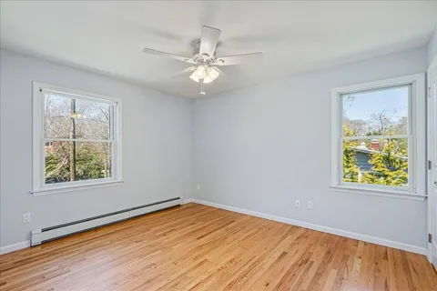 a view of empty room with wooden floor and fan