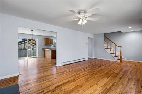 a view of an empty room with wooden floor and a kitchen