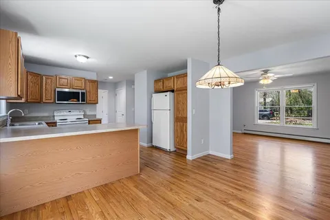 a large kitchen with stainless steel appliances granite countertop a refrigerator a stove a sink dishwasher and a oven with wooden floor