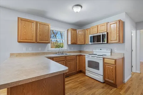 a kitchen with stainless steel appliances granite countertop wooden cabinets a stove top oven a sink and dishwasher with wooden floor