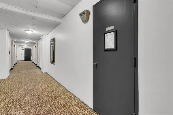a view of a hallway with wooden floor and a bathroom