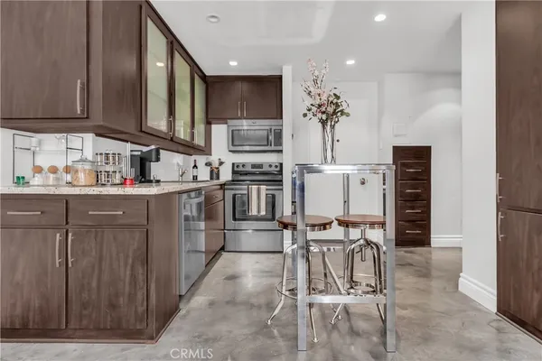 a kitchen with stainless steel appliances kitchen island granite countertop a stove top oven a sink a dining table and chairs