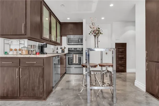 a kitchen with stainless steel appliances kitchen island granite countertop a stove top oven a sink a dining table and chairs