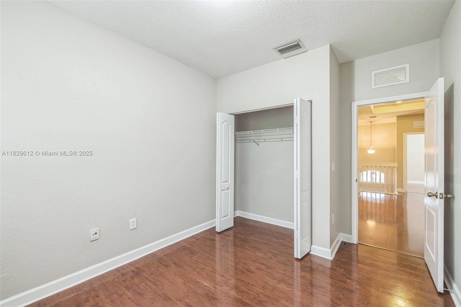 11266 Southwest 236 Lane Homestead, FL 33032 - Photo 23 of 32 a view of an empty room with wooden floor and a bedroom