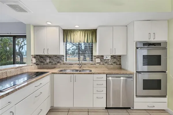 a kitchen with granite countertop a sink stainless steel appliances and cabinets